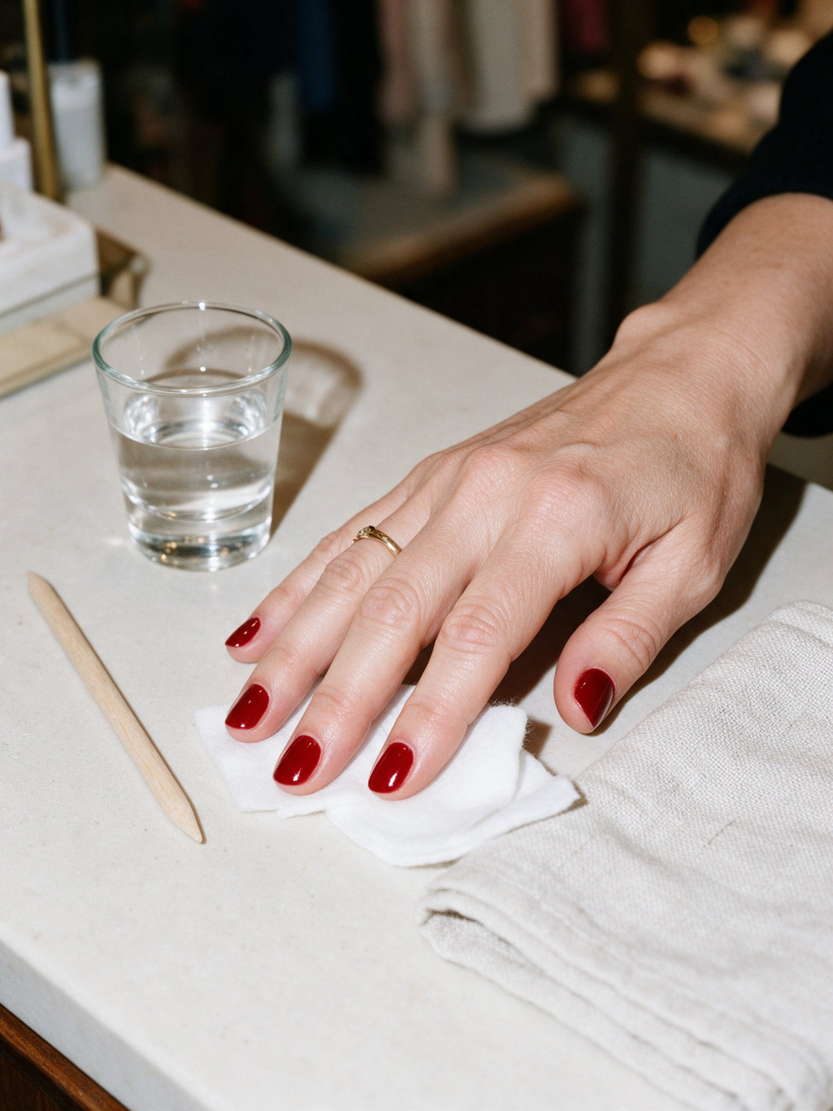 Mano con las uñas recién pintadas de rojo sobre el mostrador de la tienda